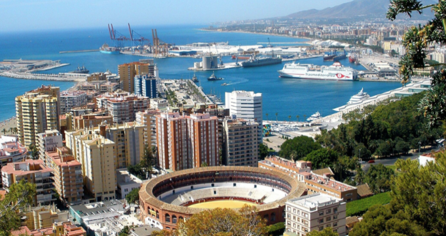 Vista aérea de la ciudad de Málaga con la histórica Plaza de Toros, el puerto con ferris y la costa mediterránea