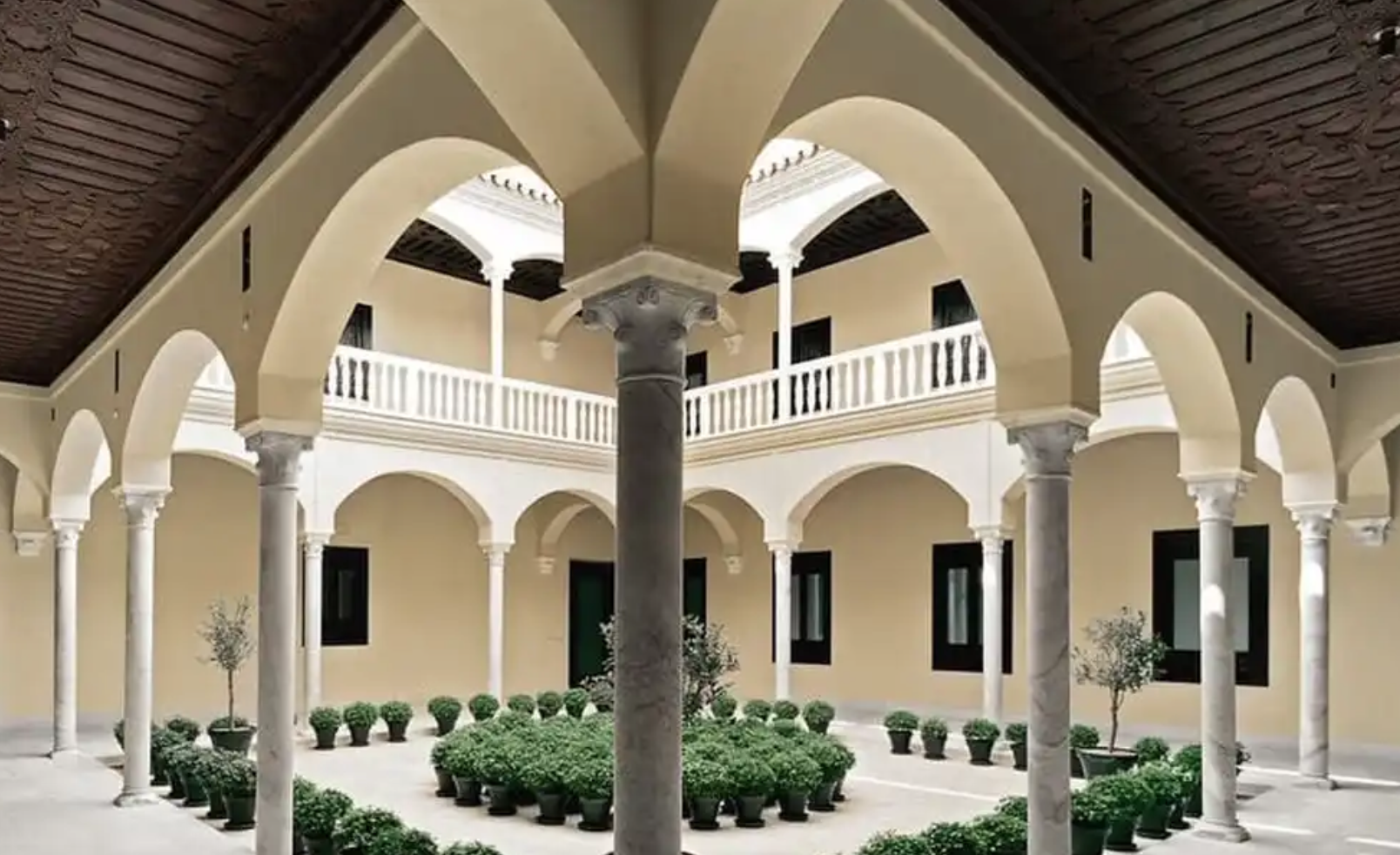 Detalle arquitectónico en primer plano de los muros de piedra dorada y ventanas clásicas de edificios históricos de Málaga